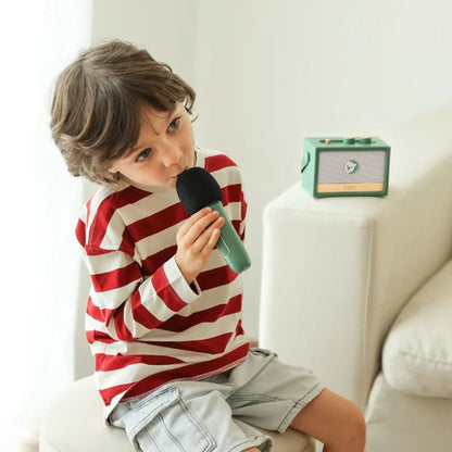 Child holding a green handheld microphone toy and small retro radio player