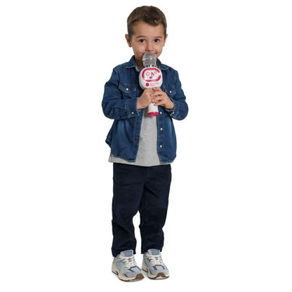 A young boy stands against a white background holding a toy microphone. He is wearing a blue denim jacket over a gray t-shirt, dark navy pants, and gray sneakers.